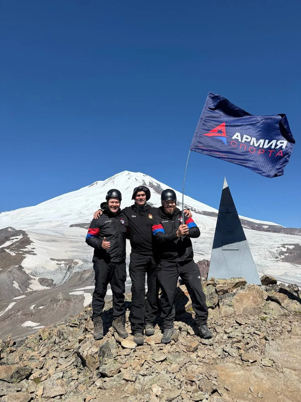 A sports team standing together on a mountain summit